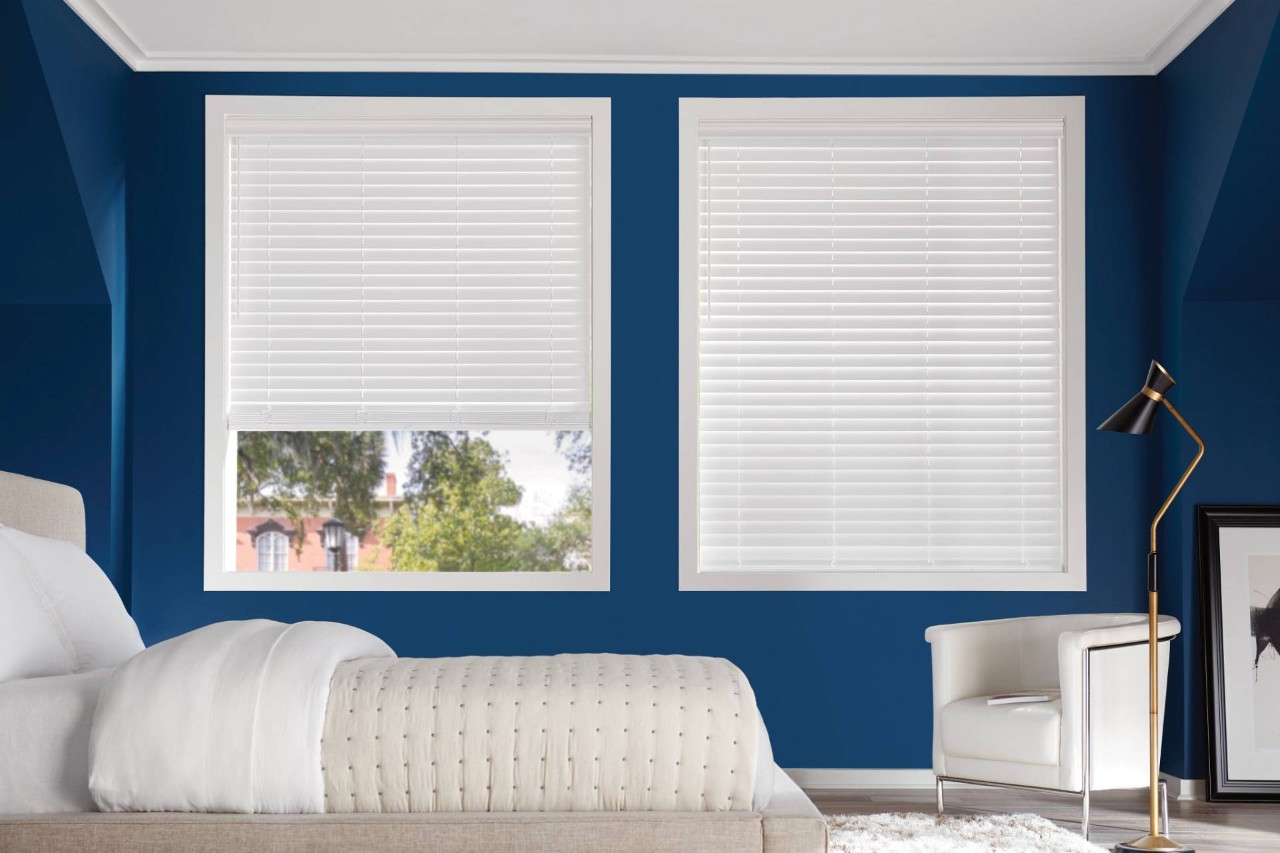 Bedroom with blue walls and two large windows covered by Hunter Douglas EverWood® Faux Wood Blinds at PSI Window Coverings near Scottsdale, AZ